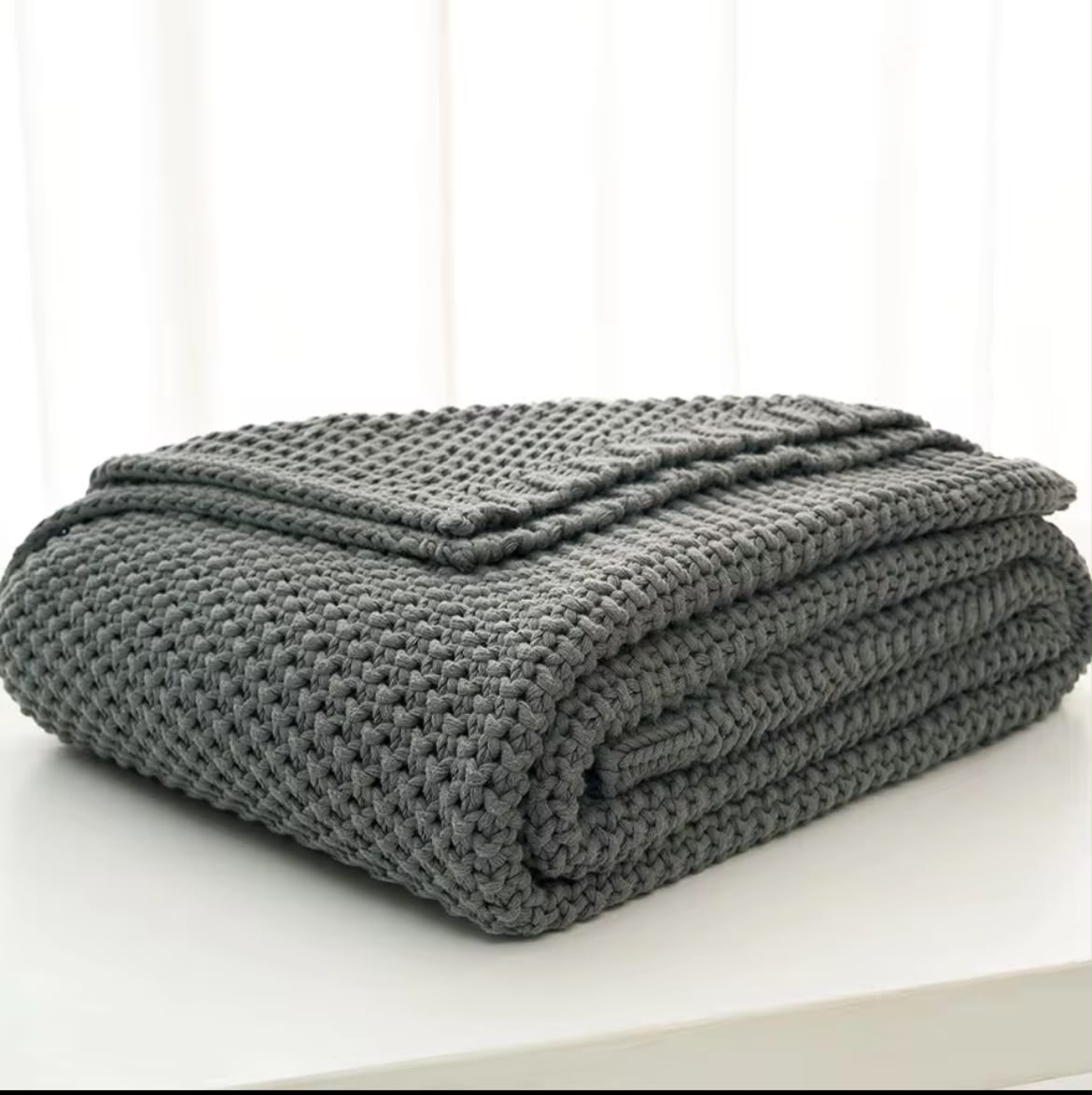 Chunky knit throw blanket white folded on white surface Nordic style
