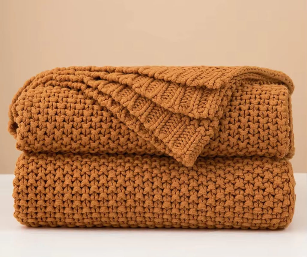 Chunky knit throw blanket beige cream folded on white surface