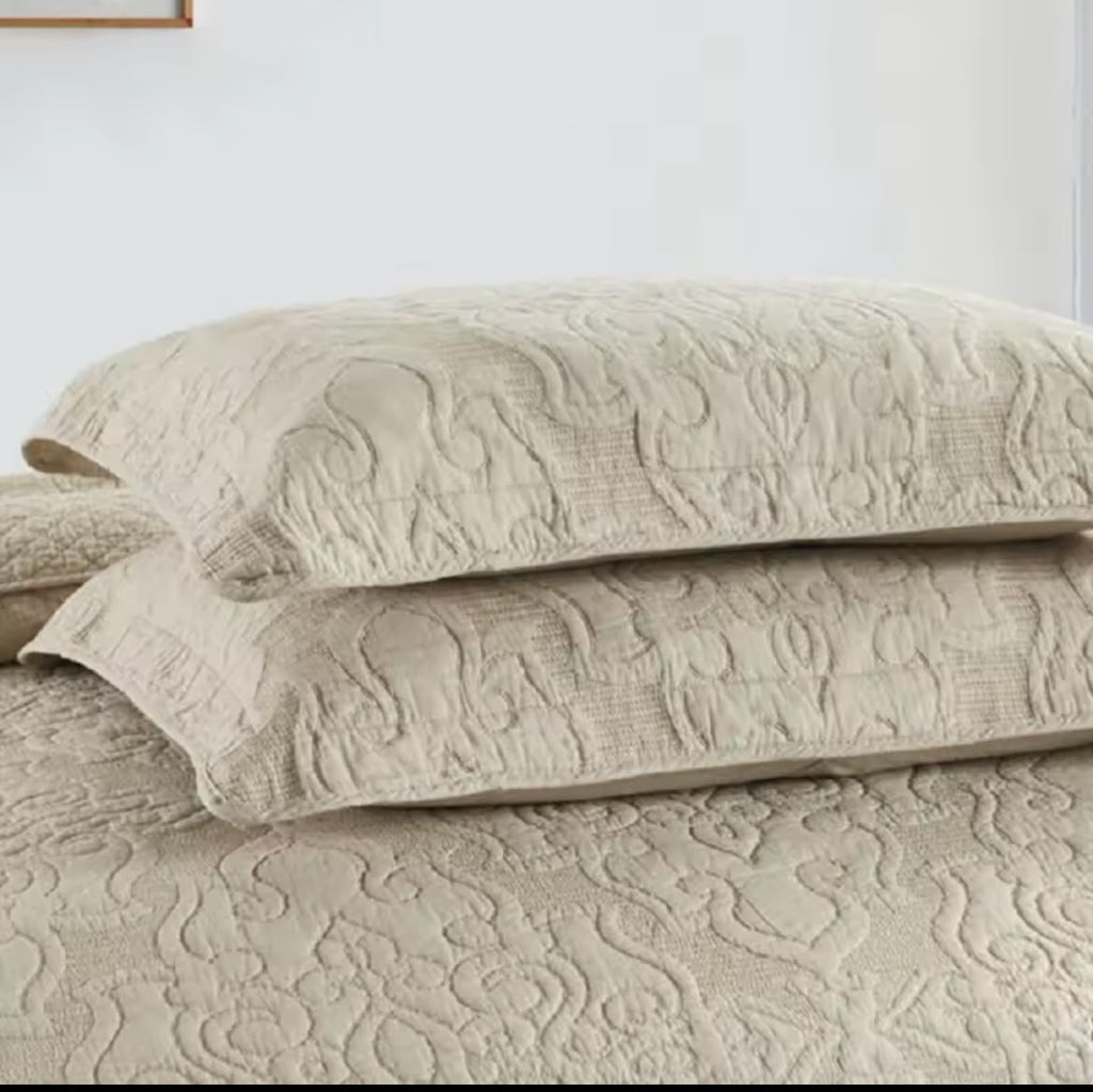 Two stacked natural beige embroidered cotton pillow shams with arabesque quilting pattern – close-up
