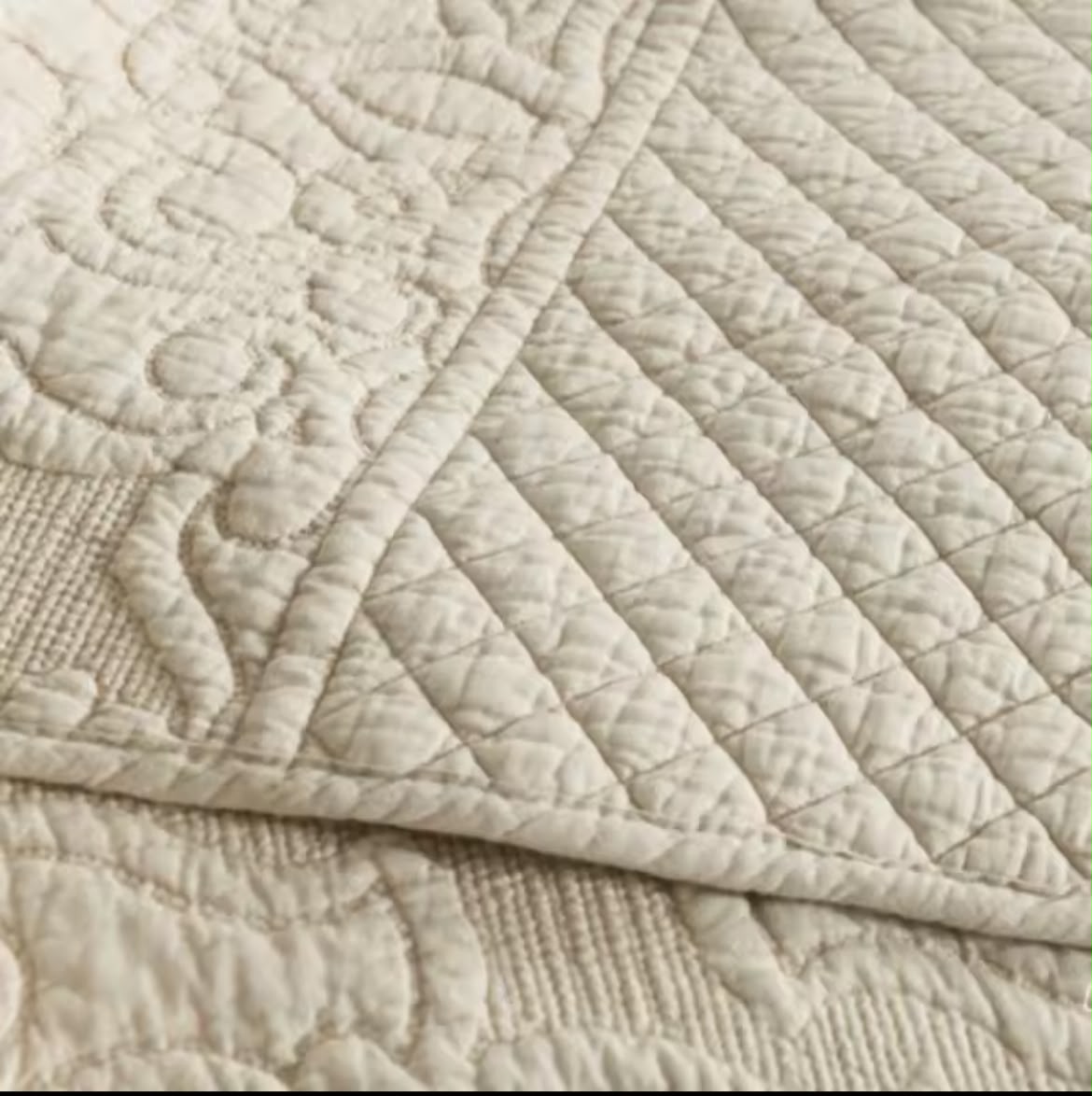 Folded corner of natural cotton quilt revealing reversible diamond quilting pattern – detail view