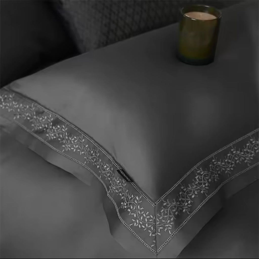 Close-up of grey Egyptian cotton pillowcase with floral embroidery border and candle