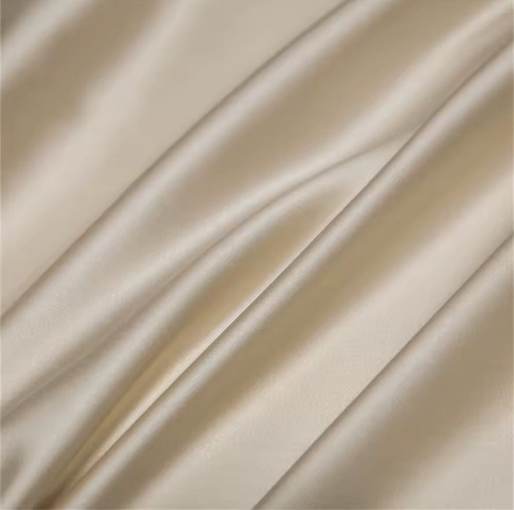 Macro texture shot of champagne silk-touch fabric showing luxurious sheen and smooth weave